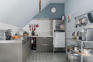 a kitchen with stainless steel appliances and a clock on the wall at Van Hamme 1642 - house for 2 to 4 persons in Kortenberg