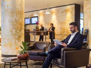 a man in a suit sitting in a chair with a laptop at Novotel London Tower Bridge in London