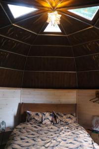 a bed in a room with a ceiling with skylights at Oku Wooden Pod, Newburgh Priory Estate in York