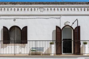 a white building with brown shutters and a balcony at La Casa Bianca in Ostuni