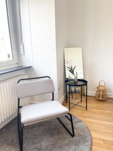uma cadeira num quarto com um espelho e uma mesa em Berchem - Guest House em Bonnevoie