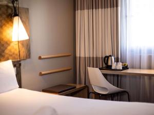 a hotel room with a bed and a desk and a chair at ibis London City - Shoreditch in London