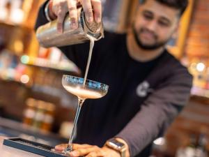 a man pours a drink into a martini glass at ibis London City - Shoreditch in London
