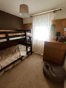 a bedroom with bunk beds and a dresser and a window at Peppercombe Chalet - Bideford Bay Holiday Park, Devon in Bucks Mills