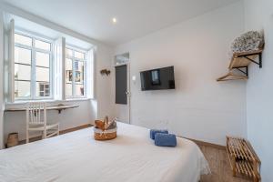a white room with a bed and a tv at Lost Lobster Guest House in Albufeira
