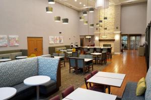Hampton Inn & Suites Chicago/Aurora في أورورا: مطعم به طاولات و كنب و طاولات و كراسي