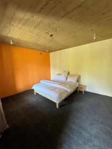 a bed in a room with an orange wall at Hostel Nomads Hunza in Alīābād