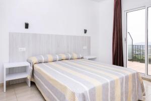 a bedroom with a bed with a striped blanket and a window at Apartamentos Torrevella in L'Estartit
