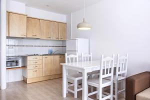 cocina con mesa blanca y sillas blancas en Apartamentos Torrevella en L'Estartit