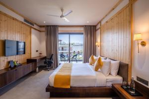 a hotel room with a bed and a television at Shervani Pebbles And Pines Corbett in Rāmnagar