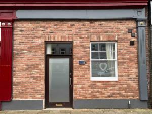 a brick building with a door and a window at The Print Room, 1 Bedroom Ground Floor Apartment in Carlisle