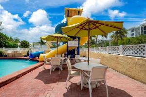 a patio with tables and chairs next to a pool at Comfort Inn Oceanside Deerfield Beach in Deerfield Beach