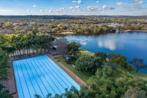 Elle offre une vue sur une grande piscine située à côté d'un lac. dans l'établissement Tonder High Performance Center, à Pretoria