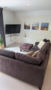 a brown couch in a living room with a flat screen tv at Sonnendeck exklusives Haus in Meerbusch - Wellness Oase Whirlpool & Grill in Meerbusch