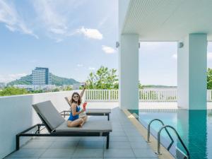 een vrouw op een stoel naast een zwembad bij Novotel Phuket City Phokeethra in Phuket