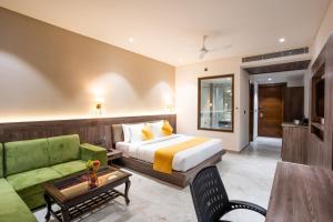 a hotel room with a bed and a green couch at Shervani Pebbles And Pines Corbett in Rāmnagar