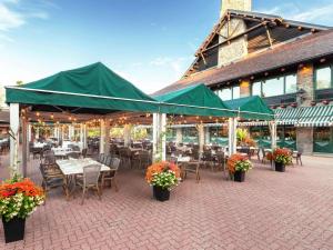 un patio al aire libre con mesas, sillas y sombrillas verdes en Fairmont Le Chateau Montebello en Montebello