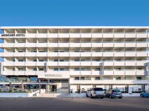un parcheggio di fronte a un grande edificio bianco di Mercure Rhodes Alexia Hotel & Spa a Città di Rodi