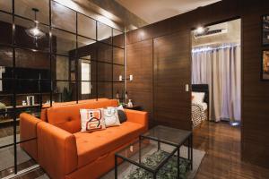 a living room with an orange couch and a table at Kensal Industrial - Air Residences in Manila