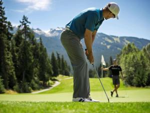 Um homem está a jogar golfe num campo de golfe. em Fairmont Chateau Whistler em Whistler