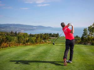 un hombre balanceando un club de golf en un campo de golf en Fairmont Le Manoir Richelieu, en La Malbaie