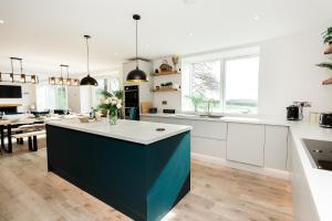 a kitchen with white cabinets and a blue island at Disdow House; luxury 5 bedroom house with views in Gatehouse of Fleet