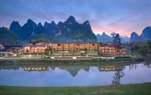 a resort with mountains in the background next to a body of water at Hilton Garden Inn Guilin Yangshuo in Guilin