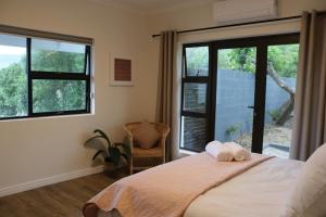 um quarto com uma cama, 2 janelas e uma cadeira em Luxurious Modern Beachfront Escape em Wilderness