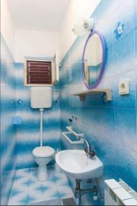 La salle de bains est pourvue de carrelage bleu, de toilettes et d'un lavabo. dans l'établissement Primošten-Huljev, à Primošten