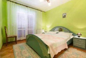 a green bedroom with a large bed and a window at Primošten-Huljev in Primošten