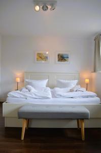 a large bed with two white sheets and two lamps at Insel Landhaus Feuerstein in Gager