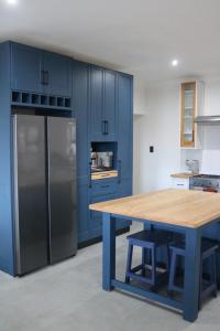 uma cozinha azul com uma mesa de madeira e um frigorífico em Luxurious Modern Beachfront Escape em Wilderness