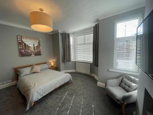 um quarto com uma cama, uma cadeira e janelas em Delightful home in Manchester em Manchester