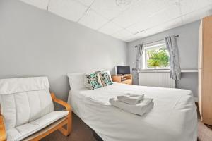 een slaapkamer met een wit bed en een stoel bij Riverside Mews in Brigg