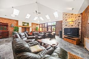 a large living room with leather couches and a television at Riverside Mews in Brigg