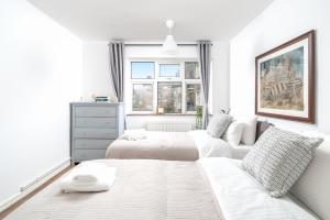 a white bedroom with two beds and a window at Luxe 3 Bedroom flat In London on Central Line for Families, Contractors, Business Travellers in Woodford Green
