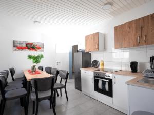 SR24 - Stillvolles gemütliches Apartment 5 in Recklinghausen في ريكلينغاوسين: مطبخ مع طاولة وكراسي وثلاجة