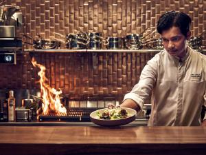 Un uomo che tiene in mano una ciotola di cibo in cucina di Pullman Singapore Hill Street a Singapore