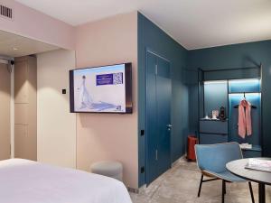 a bedroom with a bed and a tv on the wall at Novotel Hamburg Central Station in Hamburg
