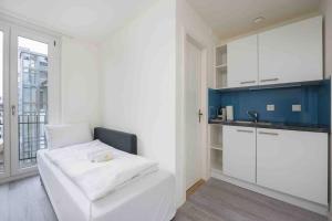 a white room with a bed and a kitchen at Cozy Urban Studio in the City BE-41 in Zürich