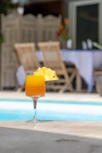 a glass of orange juice sitting on a table next to a pool at La Villa des Lataniers in Étang-Salé