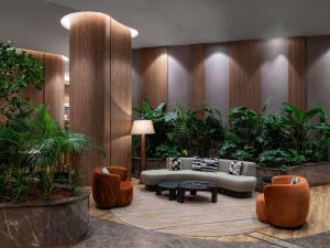 a lobby with a couch and chairs and plants at Mövenpick Living Istanbul Saklivadi in Istanbul