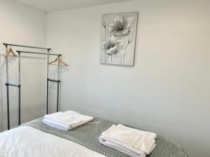 a white room with a bed with towels on it at Majestic 2 bedroom House Milton Keynes in Milton Keynes