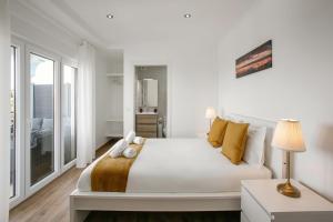 a white bedroom with a large bed with yellow pillows at Bela Vista in Atouguia da Baleia