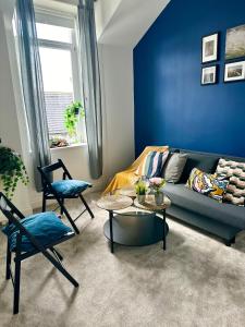 a blue living room with a couch and chairs at Cosy stylish Dumbarton flat in Dumbarton