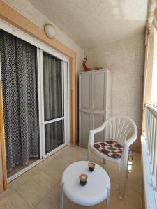 ein Wohnzimmer mit einem Stuhl, einem Tisch und einem Fenster in der Unterkunft Apartment Torrevieja in Torrevieja