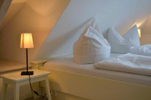 a bedroom with a bed with white pillows and a lamp at Insel Landhaus Feuerstein in Gager