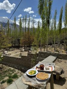 a picnic table with two plates of food on it at Hostel Nomads Hunza in Alīābād