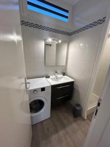 Un baño con lavadora y lavabo. en Appartement 4 personnes Mimizan, en Mimizan