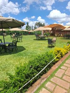 a field with tables and chairs and umbrellas at The Sailors Address in Thika